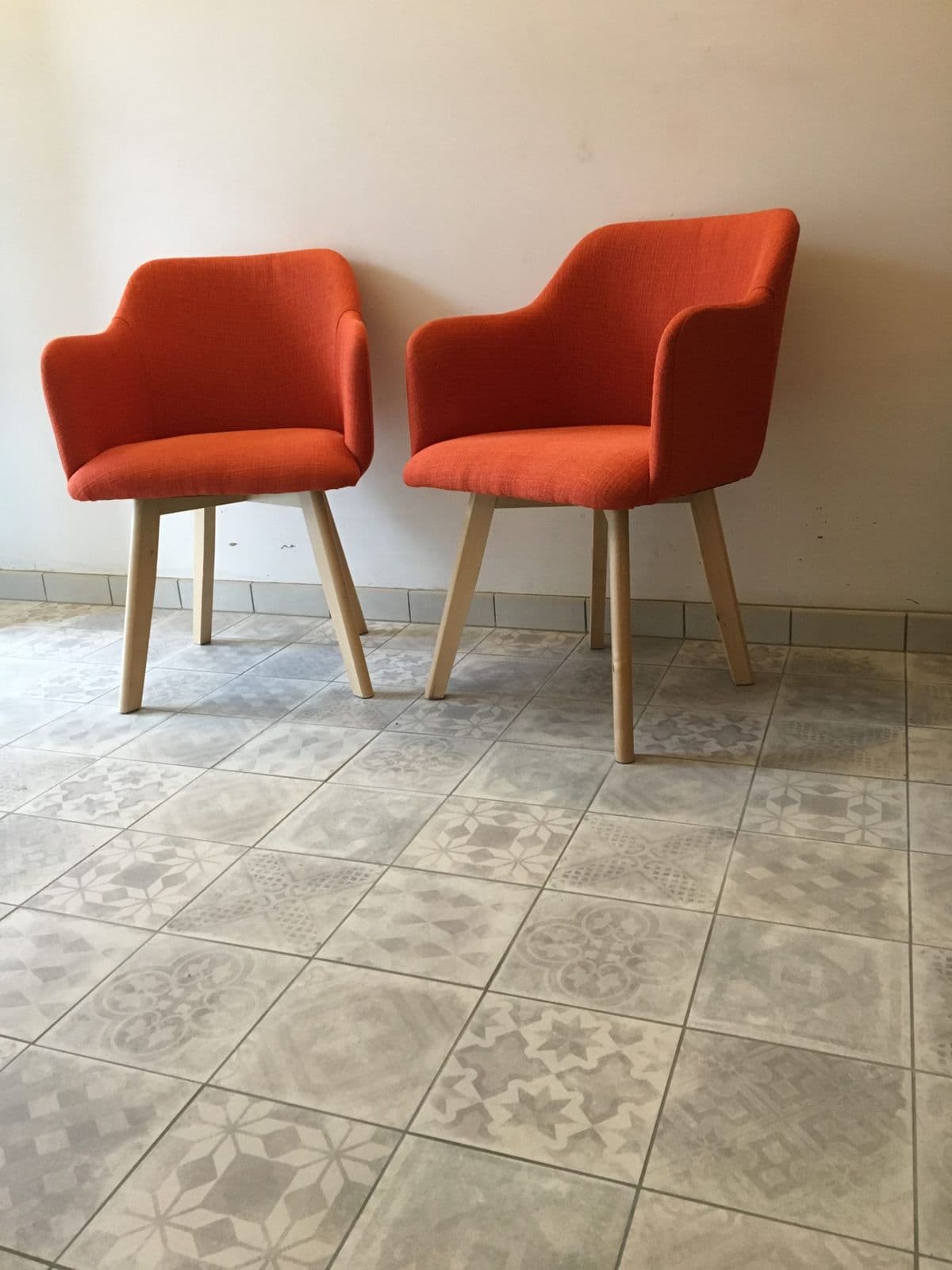 Twee oranje stoelen op een vloer van patchwork tegels